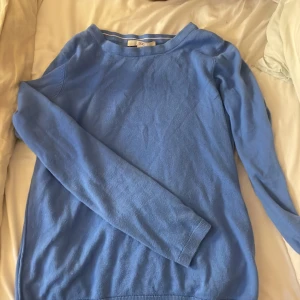 Blå stickad tröja från EDC XS - Snygg blå stickad tröja från EDC i storlek XS. Tröjan har en enkel och clean design med rund hals och långa ärmar. Perfekt för dig som gillar basic men ändå vill ha lite färg i garderoben. Mjuk och skön kvalitet som passar till jeans eller kjol.