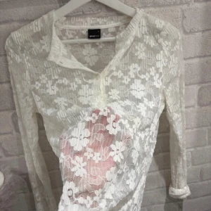 Vit spetsblus från Gina Tricot - Supersöt vit spetsblus från Gina Tricot i storlek S. Blusen har lång ärm, knappar framtill och är helt genombruten med blommigt spetsmönster. Använt 3/4 gånger.