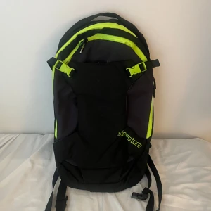 Svart och neongul ryggsäck Sledstore - Ryggsäck från Sledstore i svart och neongul polyester. Snygg och sportig design med flera fack och praktiska spännen. Perfekt för dig som vill ha en cool och funktionell väska. Justerbara axelremmar och dragkedja upptill. Perfekt för skoter eller slalom eller cykling