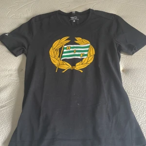 Hammarby tröja - Hammarby T-shirt i tyg material. Storlek M  . Nästan aldrig använd då ja ej tyckte att den passade mig tyvärr. Pris kan diskuteras🤍💚
