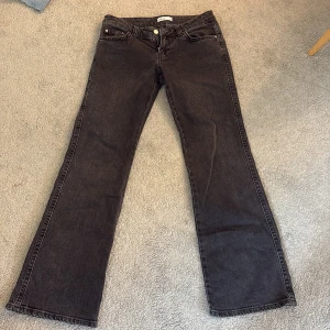 Svarta bootcut low waist  - Snygga svarta jeans från Perfect Jeans i bootcut-modell med klassisk femficksdesign och coola fickor med knapp bak. Jeansen har normal passform och är tillverkade i slitstarkt denimtyg. Perfekt för dig som gillar en tidlös look med lite extra edge.