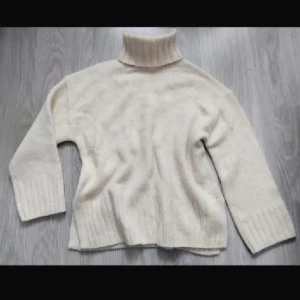 Beige polotröja från H&M - Säljer en beige polotröja från H&M i storlek S men väldigt stor i storleken mer än M. Tröjan är stickad med ribbade detaljer vid hals, ärmslut och nederkant. Den har lång ärm och en hög, mysig polokrage som ger extra värme. Perfekt för kyliga dagar och enkel att matcha med jeans eller kjol