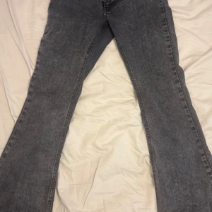 Gråa bootcut jeans - Snygga grå jeans med bootcut passform och klassisk femficksdesign. Jeansen har en cool tvättad look som ger en vintage känsla. Materialet är slitstarkt jeans och färgen är mörkgrå med lätt blekta detaljer. 