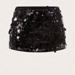 Svart paljettkjol med dragkedja - Supersnygg svart kortkjol täckt med stora och små paljetter som ger maxad glittrig effekt. Kjolen har en smickrande tight passform och stängs med dragkedja i sidan. Perfekt för dig som vill sticka ut och glänsa på nästa fest eller event. Har även inbyggda som korta shorts under