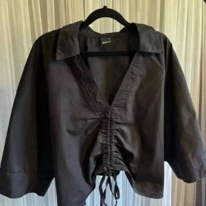 Svart croppad blus med snörning - Svart blus från Gina Tricot med croppad passform och breda trekvartsärmar. Använd fåtal gånger, som ny! 🥰