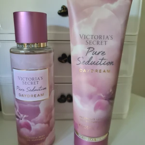 Victoria's Secret Pure Seduction Daydream set - Säljer ett set med Victoria's Secret Pure Seduction Daydream, innehållande en body mist och en body lotion. Båda har en drömmig rosa och lila design med guldiga detaljer. Doften har inslag av Plum Sugar och White Suede för en söt och mjuk känsla. Helt nytt och oanvänt 