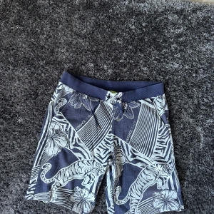 Versace Jeans blå shorts XL - Snygga blå shorts från Versace Jeans med unikt zebramönster och tigrar i vitt. De har elastisk midja med snörning och två fickor bak. Materialet är mjukt och känns som bomull, perfekt för sommaren. Stora blommor och coola detaljer gör dem riktigt iögonfallande. Shortsen finns ej till salu på Versaces hemsida vilket gör de väldigt unika, shortsen är sann till sin storlek👍 pris diskuterbart vid smidig affär🙌