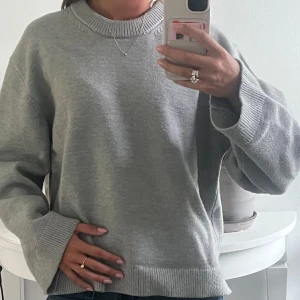 Grå stickad tröja Gina Tricot M - Säljer en enkel och snygg grå stickad tröja från Gina Tricot i storlek M. Tröjan har rund hals, ribbade muddar och är långärmad med en loose passform. 