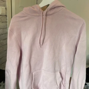 Ljusrosa hoodie från Divided XS - Säljer en ljusrosa hoodie från Divided i storlek XS. Tröjan har huva med snörning, magficka och långa ärmar. Mjuk insida och enkel.