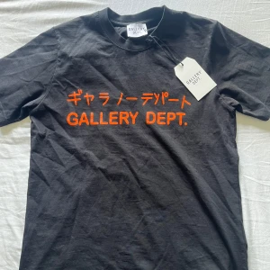 Gallery dept Tokyo tee  - Svart t-shirt från Gallery Dept. med orange tryck på bröstet i både japanska tecken och text. Klassisk rund hals och korta ärmar. Materialet är mjuk bomull, perfekt för en chill och stilren look. 