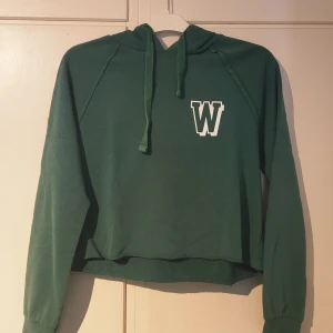 Grön hoodie Wild Wonder Gina Tricot - Grön hoodie från Gina Tricot                                 Tröjan har huva med snörning, croppad passform och långa ärmar.  Material: 65% bomull och 35% polyester. Storlek S