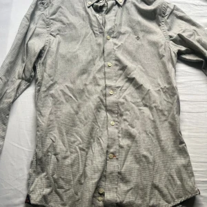 Grå rutig skjorta från Morris - Snygg grå skjorta från Morris i liten rutig design. Skjortan har klassisk krage, knäppning framtill och långa ärmar.