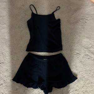 Svart linnetopp från Lindex - Svart linnetopp från Lindex med tunna axelband och enkel, stilren design. Perfekt för dig som gillar en clean look. Matchas snyggt med shorts eller jeans. Materialet känns mjukt och lätt mot huden.