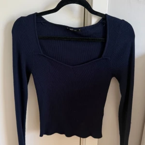 Mörkblå ribbad långärmad tröja - Säljer en mörkblå ribbad långärmad tröja från GinaTricot. Tröjan har en snygg fyrkantig urringning och är figurnära i modellen. Perfekt att matcha med jeans eller kjol för en stilren look.b
