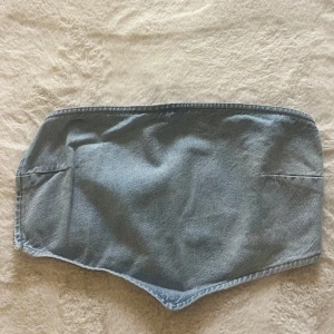 Ljusblå jeans tubtopp från NA-KD - Säljer en snygg ljusblå jeans tubtopp från NA-KD. Toppen är bandeau-modell i storlek 34. Perfekt nu till sommaren.