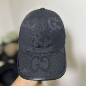 Svart keps från Gucci med GG-logga - Snygg svart keps från Gucci med klassisk GG-monogram över hela kepsen. Kepsen har böjd skärm och justerbar rem baktill. Tillverkad i slitstarkt material och har en stilren look som passar perfekt till sommaren.☀️