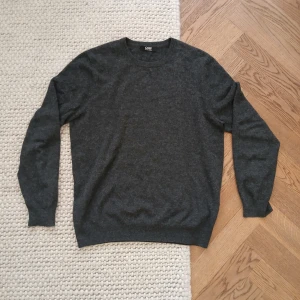 Mörkgrå kashmir tröja från Gobi - Mysig mörkgrå tröja från Gobi i 100% kashmir. Klassisk rund halsringning och långärmad modell med ribbade muddar. Perfekt för dig som gillar stilren och enkel design med lyxig känsla. Cashmere