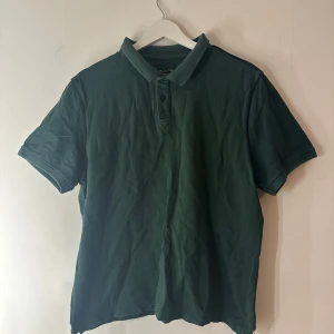 Mörkgrön pikétröja från Massimo Dutti - Snygg mörkgrön pikétröja från Massimo Dutti i klassisk modell med krage och knappar framtill. Tillverkad i mjuk bomull och har korta ärmar. Perfekt för en clean och stilren look, funkar året runt och är enkel att matcha med jeans eller shorts. Står att det är en storlek XL men är mer en M, köpt utomlands så därför storleken kan skilja sig 