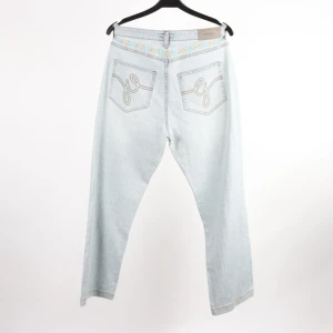Ljusblå jeans från Gant med brodyr - Snygga ljusblå jeans från Gant med broderad detalj i midjan och coola bakfickor med brodyr. Klassisk femficksmodell i bomullsmix med lite stretch för skön passform. Köpta Second hand för 500, lappen kvar, säljs för 300. Midja = 38 cm, Längd = 97 cm