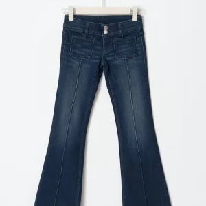 Low waist bootcut jeans - Mörkblå low waist jeans med bootcut och markerade sömmar längs benen. Byxorna har dubbla knappar i midjan och framfickor!