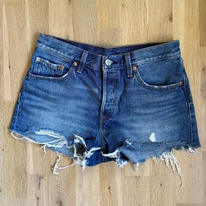 Levi's 501 original jeansshorts - Klassiska blå Levi's 501 jeansshorts med fransig kant. Medium midhöjd. Passar S, W27. Skriv om du har frågor om plagget!