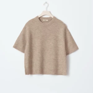 Beige stickad kortärmad tröja - Supermjuk och chill beige stickad tröja från H&M med korta ärmar och relaxed fit. Perfekt till svarta jeans eller dressade byxor. Rund halsringning och ribbade kanter ger en clean look. Passar dig som gillar enkel och stilren vibe.