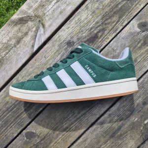 Adidas Campus gröna  - Gröna Adidas Campus i bra skick. Finns tecken på användning och har en liten skada på insidan av höger skon. Annars är skorna fortsatt fräscha och i bra skick. Skorna säljs med 2 extra snören och lådan.