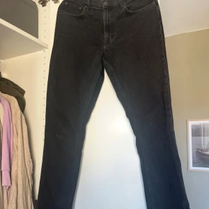 Svarta jeans med slits nertill - Säljer ett par svarta jeans med raka ben och snygg slits nertill. Jeansen har klassisk femficksdesign och är i ett mjukt denimtyg. Perfekta för dig som gillar en stilren look med en twist.