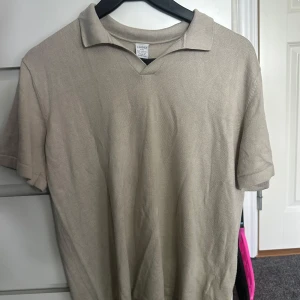 Beige pikétröja från Lindex - Snygg beige pikétröja från Lindex med klassisk krage och korta ärmar. Tröjan är i mjukt bomullsmaterial och har en enkel, stilren look som passar perfekt till jeans eller shorts. Väldigt skön på sommare