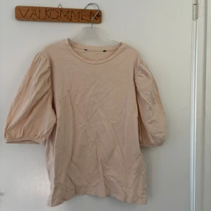 Beige blus med puffärm - Säljer en söt beige blus med puffiga trekvartsärmar och rund halsringning. Blusen har en avslappnad passform och är gjord i mjuk bomull, perfekt för en chill och stilren look. Tror att de är en stroke S men är lite osäker, vet inte var den är ifrån för lappen är bort klipp.