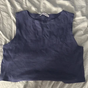 Mörkblå croppad linnetopp Fashion Friends - Enkel och stilren mörkblå croppad linnetopp från Fashion Friends. Toppen är ärmlös med rund halsringning och har en clean look som passar perfekt till jeans eller kjol. Mjuk och skön i bomullsmaterial, perfekt för varma dagar.