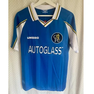 Vintage Jersey FC Chelsea  - Chelsea FC match hemmatröjan säsong 1997/1998 från Umbro med Zola 25 på ryggen. Klassisk blå färg med vita och gula detaljer, vit krage och klubbmärke på bröstet. Kortärmad modell i lätt och ventilerande material, perfekt för fotbollsälskare och samlare.