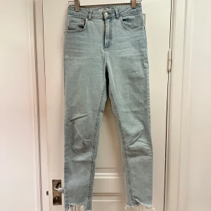 Jeans från NA-KD - Ljusblå jeans från NA-KD med en klassisk femficksdesign. De har en hög midja och raka ben med råa kanter vid bensluten. 