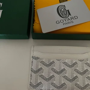 Vit plånbok - Supersnygg vit plånbok med ikoniska grafiska mönster i vit. Slimmad design med flera kortfack, perfekt för dig som gillar stilrena accessoarer. Kommer med original ask och dustbag.