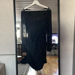 Svart glittrig långärmad klänning från SHEIN - Säljer en svart långärmad klänning från SHEIN med glittriga detaljer över hela tyget. Klänningen har en figurnära passform och är tillverkad i stretchig polyester. Perfekt för dig som vill sticka ut med lite extra glitter.