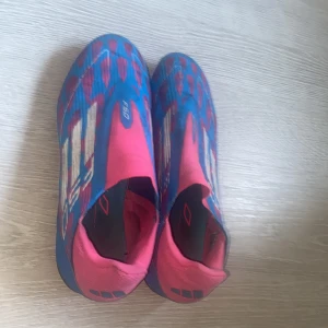 F50’s rosa och blå - F50’s som använts ett fåtal gånger, lätta skor att bära på vilket innebär att det får dig blixtsnabb på planen. Inga skador någonstans på skon. Dessutom finns det inga snören på skorna vilket underlättar situationen med att knyta. 