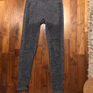 Grå träningstights från Panos Emporio - Säljer ett par grå träningstights från Panos Emporio med hög midja och snygga håldetaljer längs benen. Tightsen är stretchiga och sitter tight, perfekta för gymmet eller yoga❤️Funkar M - XL ❤️original pris: 439kr