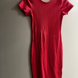 Rosa ribbad klänning från BikBok - Säljer en rosa ribbad klänning från BikBok med tight passform och korta ärmar. Klänningen har rund halsringning fram och djup, öppen rygg. Perfekt för dig som gillar enkel men snygg stil.