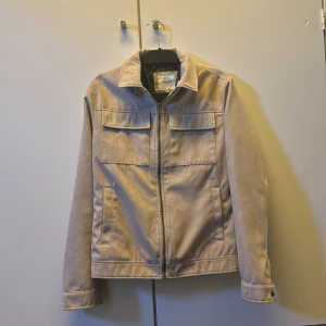 Beige mocka jacka från Jack & Jones - Säljer en stilren beige mocka jacka från Jack & Jones med klassisk krage och dragkedja framtill. Jackan har två bröstfickor med lock och raka ärmar. Perfekt för dig som gillar enkel och clean stil. Nypris på denna är runt 1599, mitt pris 499! Pris går att diskuteras! Hör av er vid minsta lilla fundering🤗