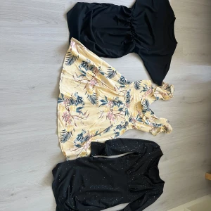 Tre klänningar i olika stilar - Säljer tre snygga klänningar! En svart kortärmad klänning med markerad midja, en ljusgul blommig klänning med volangdetaljer och en svart glittrig långärmad klänning. Perfekta för olika tillfällen och stilar.