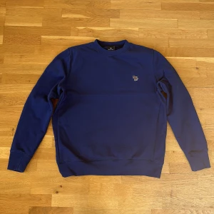 Tjocktröja från Paul Smith - Säljer en riktig snygg blå tjocktröja från Paul Smith i storleken L. Tröjan är i mycket bra skick, inga defeker! Den är inte så stor för att vara storlek L ändå