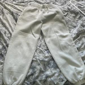 Vita mjukisbyxor med resår - Säljer ett par vita mjukisbyxor med resår i midjan och vid bensluten. Byxorna har en avslappnad passform och är perfekta för en chill dag hemma eller till vardagslooken. Materialet är mjukt och skönt mot huden. Är lite noppriga så därav priset