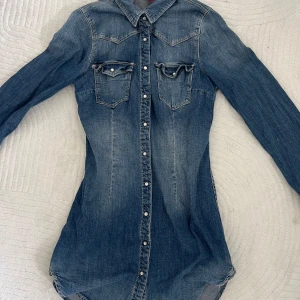 Jeansklänning med knappar - Snygg blå denim klänning med lång ärm och knappar hela vägen framtill. 
