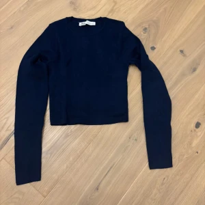 Svart croppad tröja från Zara - En enkel svart croppad tröja från Zara med rund halsringning och långa ärmar. Perfekt att styla med höga jeans eller kjol för en clean look.