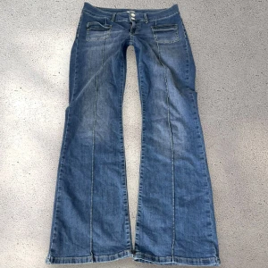 Blå bootcut jeans med låg mdija  - Bootcut jeans med låg midja från Nelly! Står ingen storlek men skulle gissa på L då midjemåttet är 42cm rakt över plus stretch. Mycket bra skick. Nypriset är 699kr
