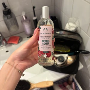 Cherries & Cheer Body Mist från The Body Shop - En fruktig och söt body mist med doft av körsbär och mandelmjölk från The Body Shop. Flaskan är genomskinlig med ett färgglatt etikettmotiv av körsbär och blommor. Vegansk formula och praktisk sprayflaska på 100 ml.