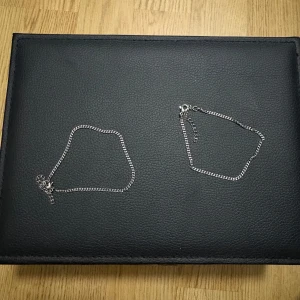 Två tunna silverfärgade armband - Säljer två stilrena och tunna armband i silverfärg med klassisk kedjedesign. Perfekta för dig som gillar minimalistiska smycken och vill ha något enkelt men snyggt på handleden. Båda har smidig karbinlås och justerbar längd.