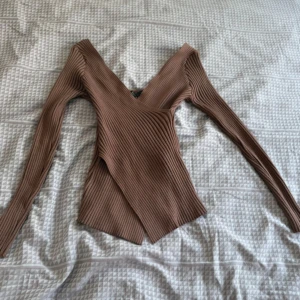 Brun shapewear tröja - Säljer en brun ribbad topp med lång ärm och snygg v-ringning. Toppen har omlottdesign och är figurnära med en lite asymmetrisk nederkant. Det är tajt passform och formar kroppen verkligen (ser mindre ut än själva storleken men stretchig) fast ändå skön och andningsbar. Tröjan tillverkas inte längre och befinner sig i bra skick då den är använd fåtal gånger. Som sagt tröjan ger en hourglass ⏳figur och ser bättre på än på bilderna.
