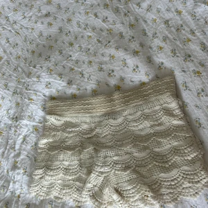 Beige virkade spets-shorts - Supersöta beige shorts med virkade spetsdetaljer och vågigt mönster. De är ganska lågmidjade och har en mjuk, elastisk midja. Perfekta för sommarens varma dagar och ger en romantisk, boho-vibe till din outfit. Shortsen har ett hål i spetsen undertill