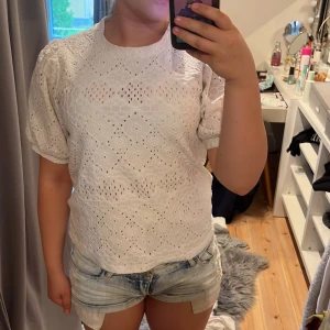 Vit blus  - Superfin vit blus med puffiga korta ärmar. Blusen har rund halsringning och är tillverkad i ett luftigt bomullstyg med spetsdetaljer. Perfekt för en fräsch och somrig look!